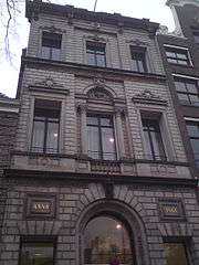 Three-story building in grey stone with the text "Anno 1861." on the facade