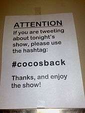 A sign indicating which Twitter hashtag to use when tweeting about the performance.