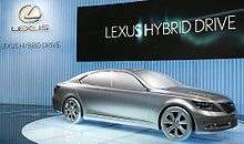 solid full-size car model on turntable, with "Lexus Hybrid Drive" listed behind.