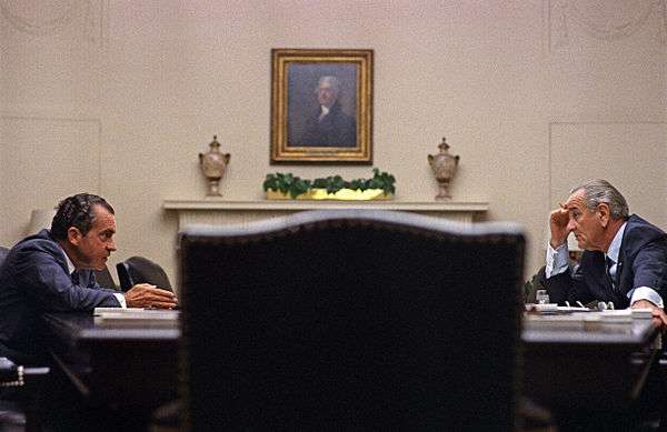 Nixon sits across a large table with President Johnson in the White House