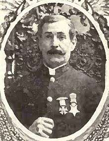 Circular portrait of a white man with a mustache wearing a military jacket with two medals pinned to the chest.