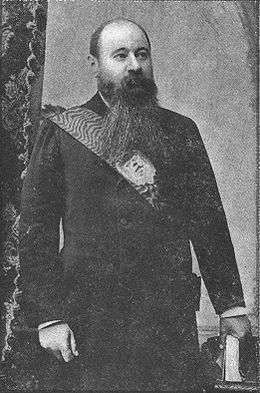 A man with an enormous dark beard wearing a sash of state