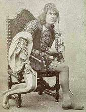 man in 16th century costume sitting in chair