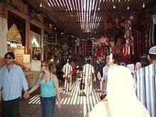 A photograph of a busy passageway leading from the foreground to the background contains people walking in both directions illuminated by elongated slats of light.