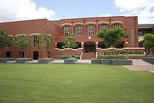 A large red brick building surrounded by trees.