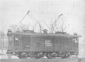 Boxy locomotive with two pantographs raised to contact overhead lines