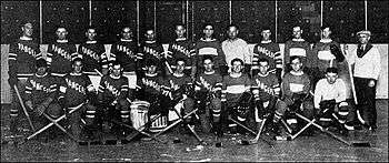 several men in hockey uniforms in two rows left to right on ice in