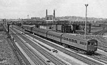 A black and white image of an electric multiple unit on the furthest of four tracks.