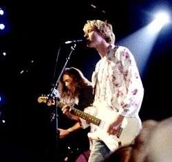 A color photograph of two members of the band Nirvana on stage with guitars