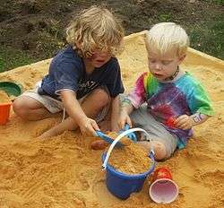 Young boy and girl filling a pail in a sandbox