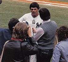 Lou Piniella, in his Yankee uniform, takes questions from the press on a baseball field