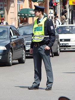 Policeman standing in street, wearing safety vest