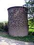 A cylindrical brick structure standing by a footpath.