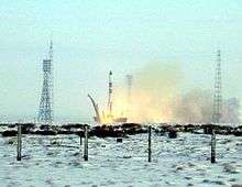 Picture of a rocket launch. The ground near the launch pad is covered in snow.