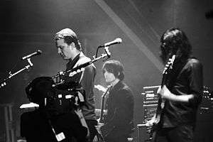 Black-and-white photograph of Queens of the Stone Age performing live in 2007.