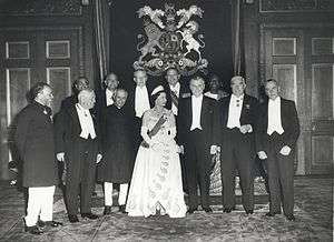 A formal group of Elizabeth in tiara and evening dress with eleven politicians in evening dress or national costume.