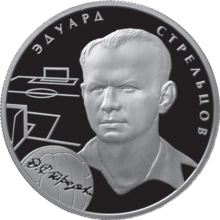 A silver coin with Strelstov's head and neck illustrated in relief upon it, accompanied by the outlines of a football pitch and a football and his name in Russian.