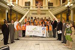 Governor Perdue, GEMA director Charlie English, ReadyKids mascot Rex the mountain lion, and Georgia elementary school students pose with a banner at Ready Georgia's official launch
