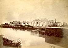 Photograph showing a canal running alongside a grand, white villa