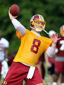 Grossman, in yellow non-contact practice jersey, throws a football in a Washington Redskins practice.