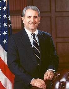 man in business suit, American flag in background