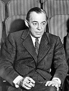 Photo of Rodgers in middle age, seated in a theatre, wearing a suit and holding a cigarette