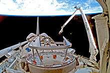A shuttle in space, with Earth in the background. A mechanical arm labelled "Canada" rises from the shuttle