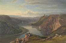 Two small figures sit on a cliff top above a river, which snakes through a wooded gorge towards the distant sea. Small boats sail along the river.