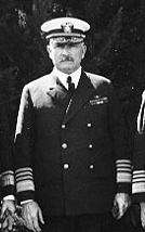 A black-and-white image of a tall man with a mustache in a naval uniform