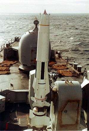 A large white missile sits on its launcher at the front of a warship.