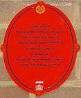 Oval red plaque bearing the words "In memory of District Officer Charles Pearson of the London Fire Brigade who died from injuries received at 100 Sidney Street near this site during the siege of Sidney Street on the 3rd of January 1911."