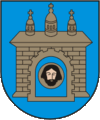 A coat of arms depicting a grey castle with three towers topped by crosses with a human head on the front door all on a blue background