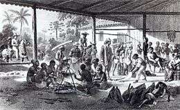 An etching depicting the interior of a large, open-sided shed with shirtless men huddling around a cooking pot in the foreground, various figures engaged in other activities in the background, and mounted riders entering the building from the left side of the picture