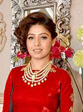 Sundihi Chauhan wearing a red top, looking at the camera half smiling