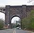 A brick arch over a road, with the start of an iron arch on the left.