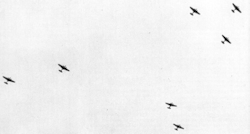 A distant photo taken from ground where several bombers are flying in the air.