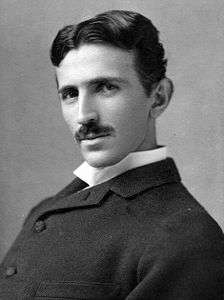 head-and-shoulder shot of slender man with dark hair and moustache, dark suit and white-collar shirt