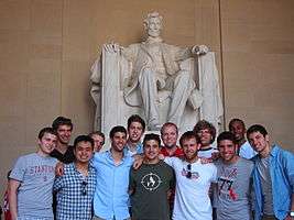 A thirteen-man group posing in front of the Lincoln Memorial.