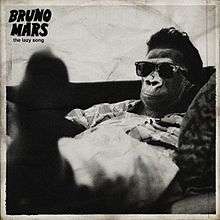 A greyscale illustration of a chimpanzee wearing a dress shirt, pants, and sunglasses. The animal is seen reclining, with his or her feet outstretched and in the foreground. In black, the words "The Lazy Song" appear in minuscule below the words "Bruno Mars" in majuscule font.