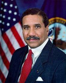 man in business suit, American flag in background