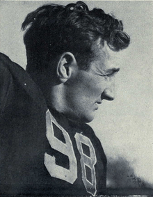 A football player wearing a dark jersey with the number 98 on it.