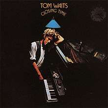A man leans against a piano in a dark room. The arched text above him reads "Tom Waits Closing Time."