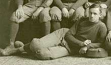 Posed sepia-toned photograph (apparently cropped from a team photograph) of Hughitt wearing a football uniform reclining on the floor