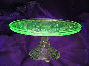 A glass place on a glass stand. The plate is glowing green while the stand is colorless.