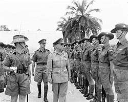 A senior military officer walking among a line of soldiers.