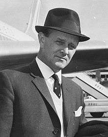 William Harper at an airport, wearing a hat