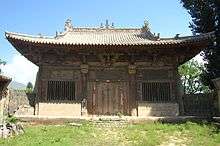 The Main Hall of Yanqing Temple. There is blue sky behind the hall. There is one door opening to a grassy courtyard