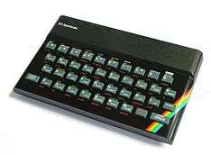 A black, rectangular box with rounded sides. A top panel reads, in raised lettering and a robotic typeface, "sinclair", and below that, in modern, white lettering, "ZX Spectrum". A full QWERTY keyboard with Chiclet buttons, full number set, and buttons for Enter, Caps Shift, and Space. Each of the buttons has alternative text in green and red lettering nearby, to access other functions when the corresponding modifier key is pressed. A red, yellow, green, blue rainbow streak shows in the right corner, but rest of the machine is black.