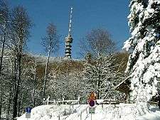 Tall antenna tower against blue sky on snowy mountain